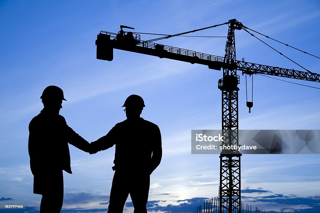 Operai edili con gru agitano le mani sotto - Foto stock royalty-free di Stringersi la mano