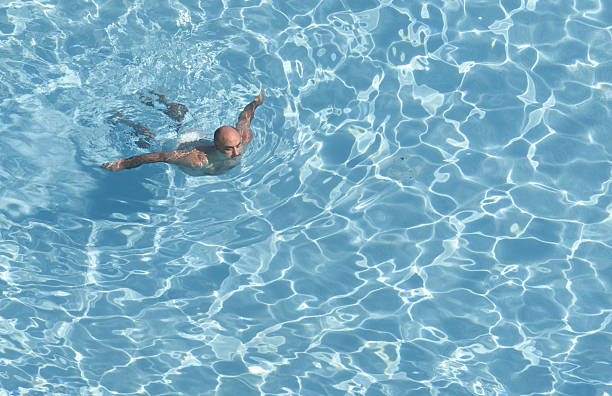 istock Middle age Bald Man swimming in pool 183797685