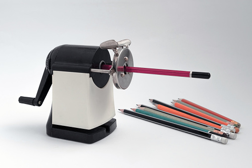 Manual sharpener against the background of already sharpened pencils