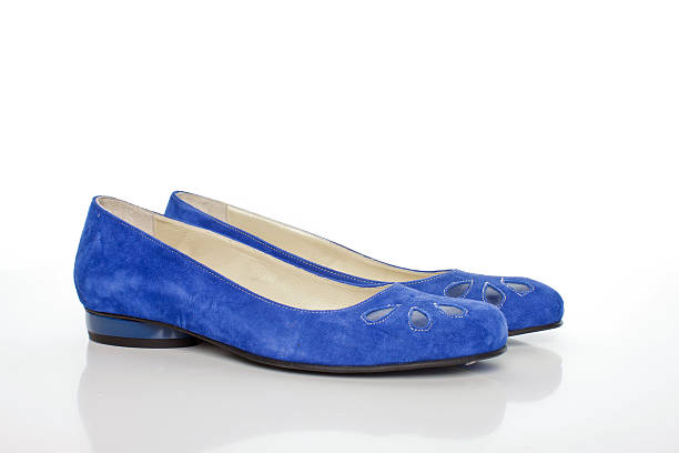 Blue high-heeled shoe is lying on white fur rug. High quality photo
