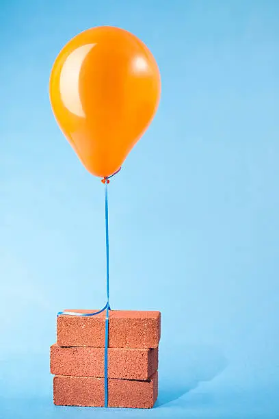 Photo of Balloon tethered to three red bricks