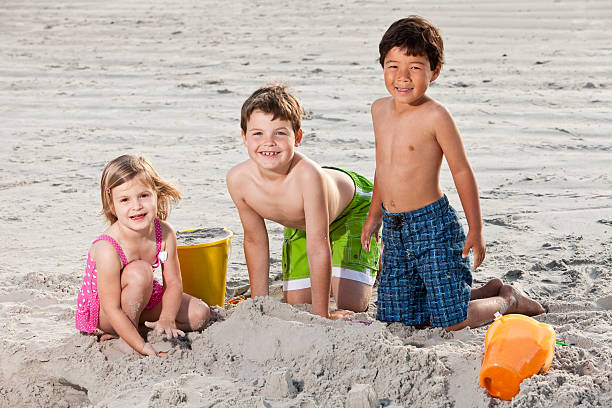 istock Multiracial friends playing in sand at the beach 183799409