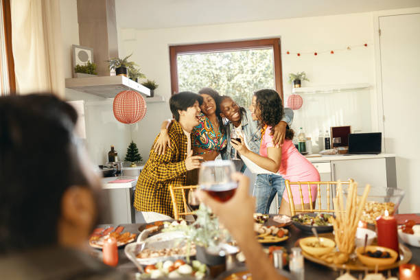 istock Cheerful young group of diverse friends holding drinks and hugging at home kitchen during party time 1837998659