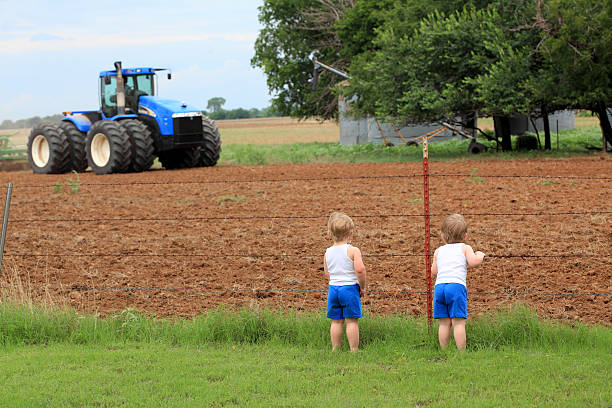 istock Agriculture: Twin Boys on the Farm watching tractor plow field 183800104