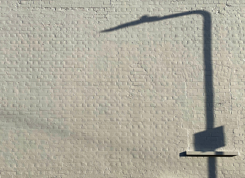 Abstract shadow of a street light on a painted brick wall in Ilford