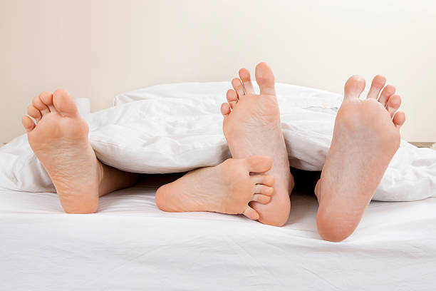 若いカップルはベッドでの融合 - sole of foot human foot women humor ストックフォトと画像