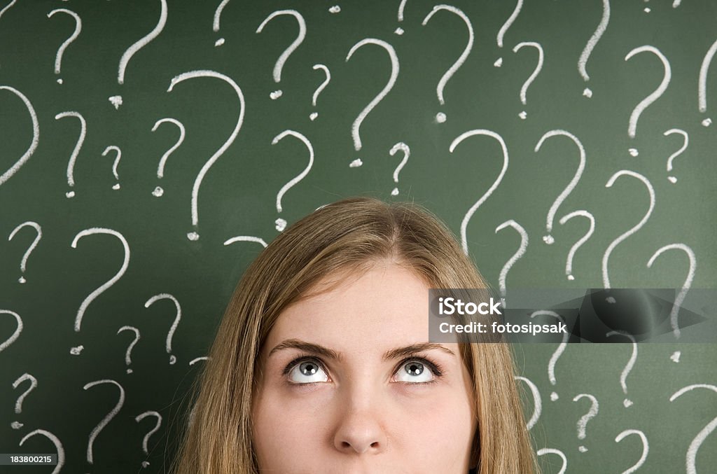 Chalk question marks above woman at blackboard thinking woman in front of question marks written blackboard Confusion Stock Photo