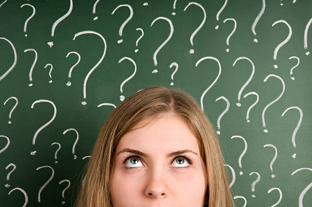 Chalk question marks above woman at blackboard thinking woman in front of question marks written blackboard suspicion photos stock pictures, royalty-free photos & images