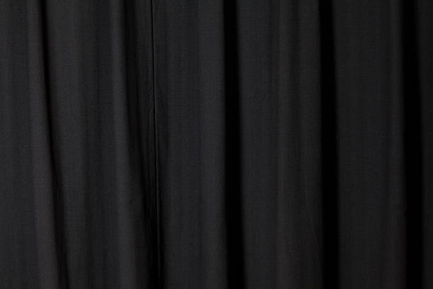 Dark Black Curtain Folded at a Theater Dark Black Curtain Folded at a Theater. hanging fabric stock pictures, royalty-free photos & images