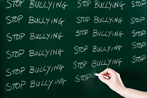 Stop bullying sentence written repeatedly on blackboard as a punishment. Focus is on the text block on the left