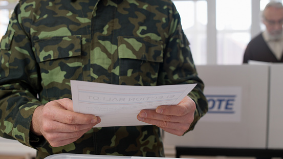 A male soldier holding a voting ballot in his hands after making his choice in the U.S. elections