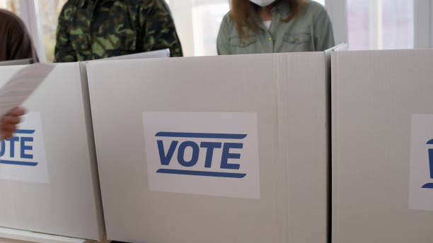 istock Citizens in protective masks voting at the polling station, participating in elections amid the pandemic 1838016034
