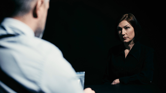 A male detective is showing an evidence bag to an impudent suspected woman during interrogation