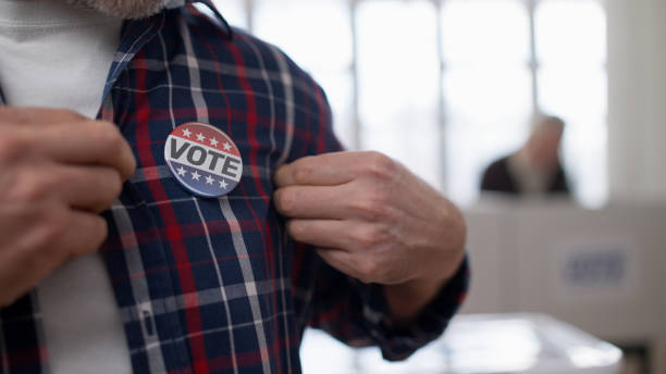 istock A responsible citizen showing a vote pin on his chest, emphasizing people voting at the polling place 1838018229