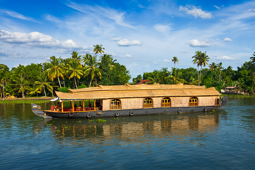 A houseboat sailing in Kerala backwaters during sunset.