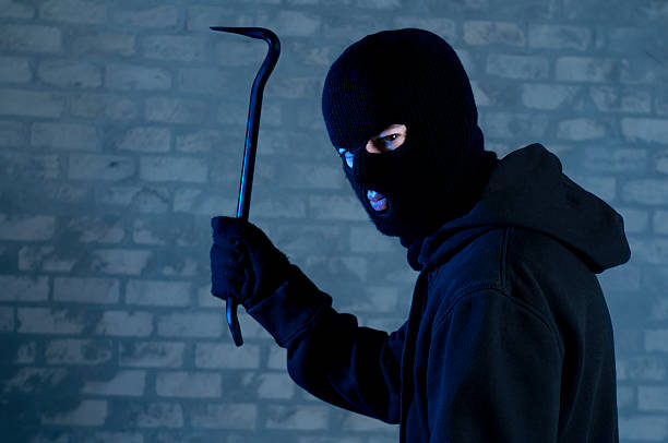 Criminal raises crowbar ready to hit Criminal disguised with balaclava raises a crowbar above his head: ready to attack or trespass. burglary crowbar stock pictures, royalty-free photos & images