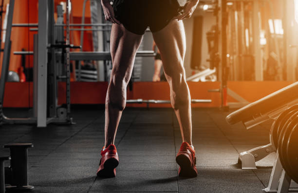 trained legs with muscular calves in sneakers in fitness training gym toned image - men body building human muscle muscular build imagens e fotografias de stock