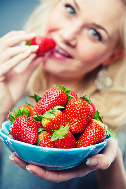 istock woman eating strawberries 183804038