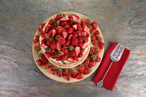 Tasty cake with fresh strawberries and mint served on gray table, top view