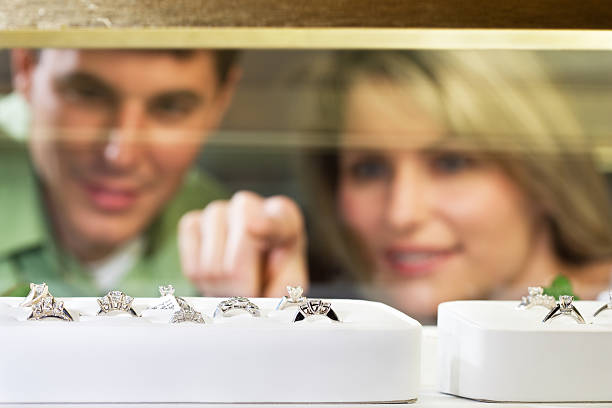 shopping for Jewelry Young couple choosing engagement ring in Jewelry store.  Focus on Diamond ring. display cabinet photos stock pictures, royalty-free photos & images