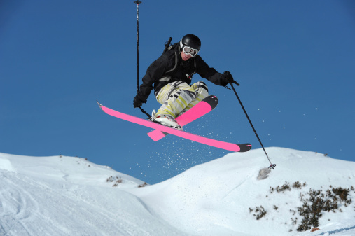 Front view of young male free ride skier in mid-air against the blue sky