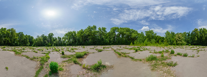 Panorama of abandoned park with an overgrown asphalt playground