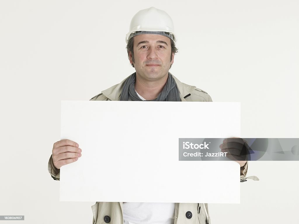 Sorridente architetto maschio tenendo il banner vuoto su sfondo bianco - Foto stock royalty-free di Industria edile