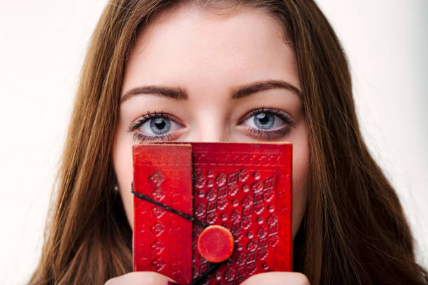 Clutching a diary, her eyes, rimmed with intrigue, invite onlookers to ponder the thoughts hidden behind its pages