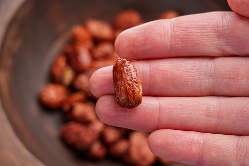 Sweet candied almond in hand. Homemade treats made from nuts with sugar. Close up