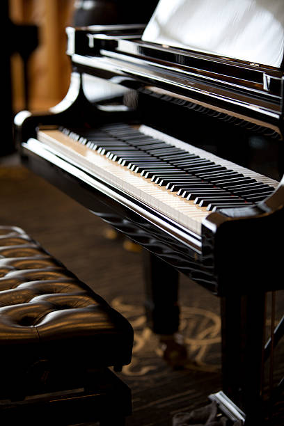 Grand Piano Close-up "Close-up of a high-end grand piano and leather stool, shallow depth of field." expensive grand piano stock pictures, royalty-free photos & images