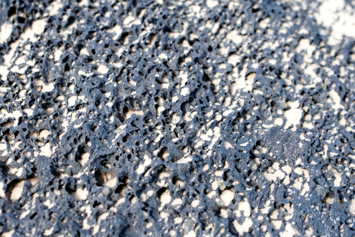 piece of black volcanic pumice with sand close up