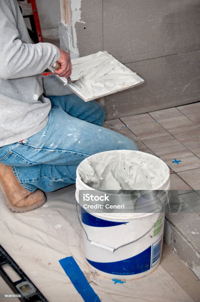 Bathroom Remodeling: Contractor putting mortar on Tiles Bathroom Remodeling: Contractor putting mortar on Tiles using a trowel Mixing Stock Photo