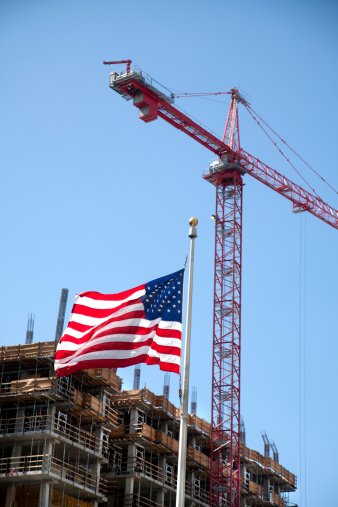 An American flag and a large construction crane
