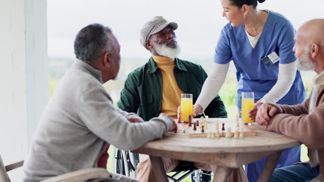 Caregiver, senior and man with juice in retirement home for health with friends for visit, chessboard and game in garden. Elderly people, patient and together for bond with organic, fresh and drink