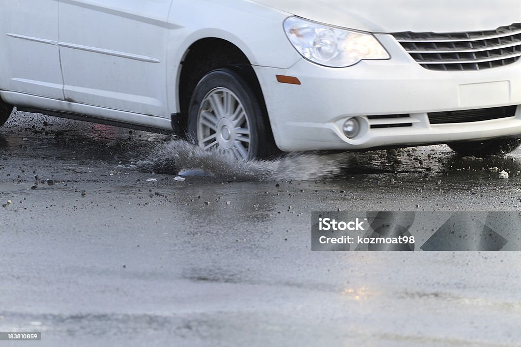 Hitting A Pothole "A car hits a pothole on a city street, throwing up water and debris. Shallow dof with focus only on the pothole and water splash." Pot Hole Stock Photo