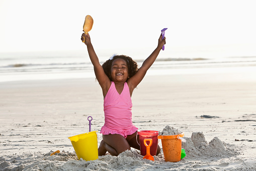 African American girl, 7 years, playing in the sand with buckets and shovels