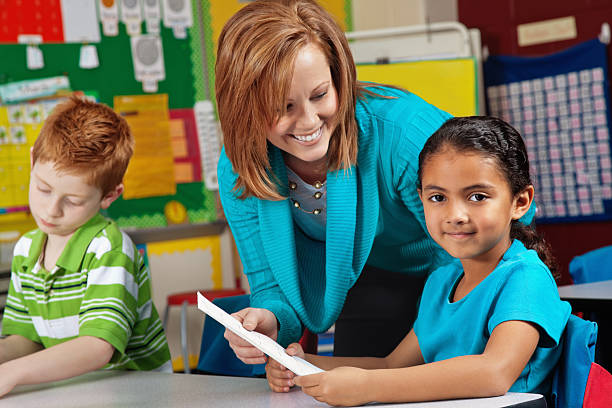 istock Little Elementary Girl Receiving Test Paper Back From Teacher 183812564