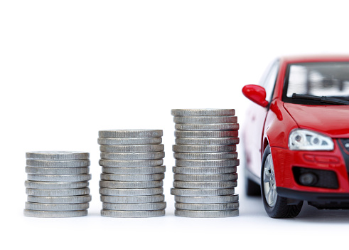 Coin rolls and a red car, isolated on white background.