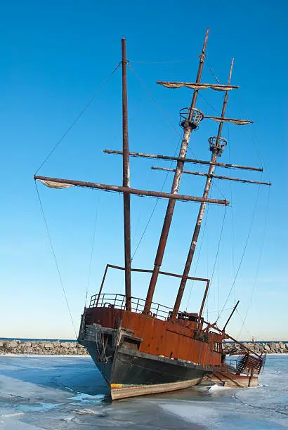 A winter capture of a ship wreck in the frozen water in the Grimsby Harbour under blue skies.