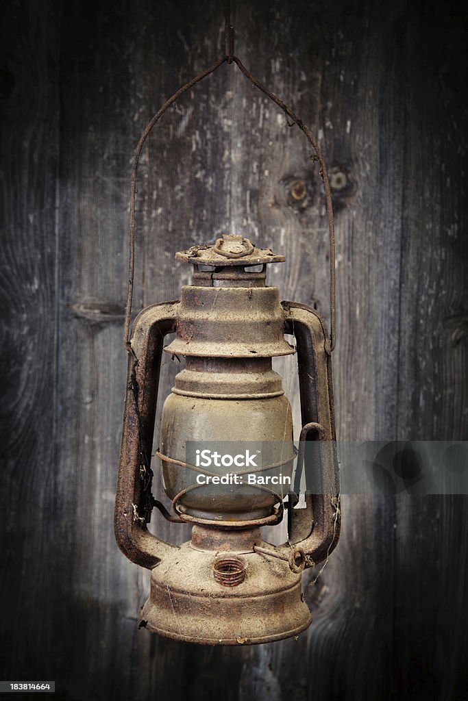 Old oil lamp Old rusty oil lamp hanging against wooden background Ancient Stock Photo