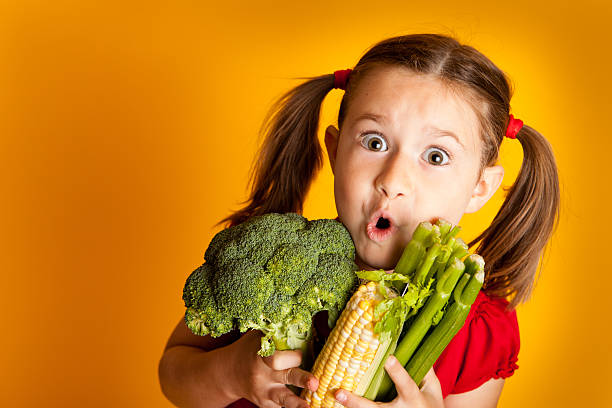 istock Excited Young Girl Holding Broccoli, Corn, Celery 183814948