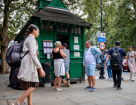 Tourists queueing to buy food and drink at a cabmen’s shelter window on the Embankment, near London’s Charing Cross Station. Cabmen’s shelters were originally for the sole use of ‘cabbies’ who needed somewhere for rest and refreshment during their working day and only those who have done ‘The Knowledge’ - an extremely difficult test which all London ‘cabbies’ have to undertake before they can be licensed and therefore able to drive a London taxi - are allowed to go inside, though the public may buy refreshments from the window. They are all Grade II listed buildings.