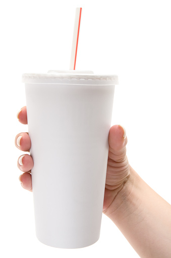 Female hand holding a white disposable soda cup with drinking straw. Isolated on a white background.