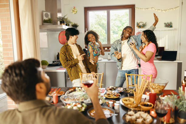 istock Cheerful young group of diverse friends holding drinks and dancing at home kitchen during party time 1838154680