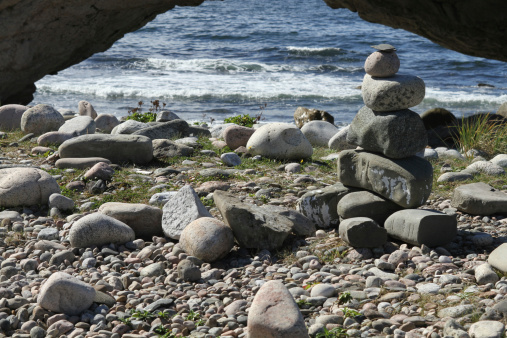 stacked stones on a beach under a natural arch - Arches Provincial Park, Newfoundland