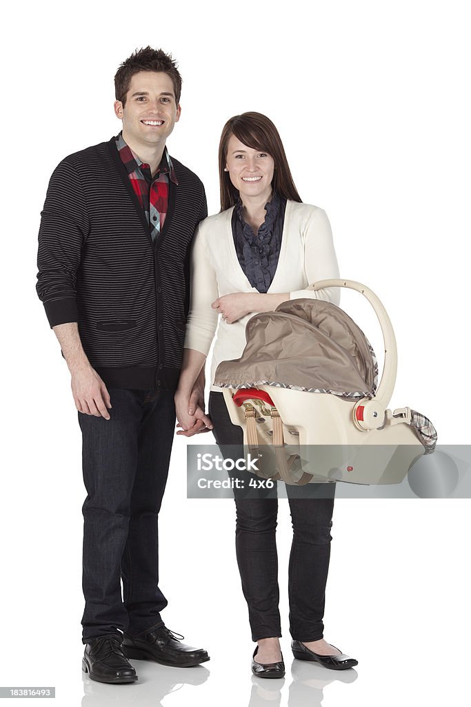 Couple standing with a baby carrier Couple standing with a baby carrierhttp://www.twodozendesign.info/i/1.png Baby Carrier Stock Photo