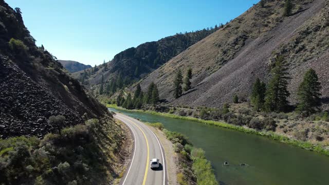 Car driving on two lane road next to snake river in Idaho Rocky Mountains