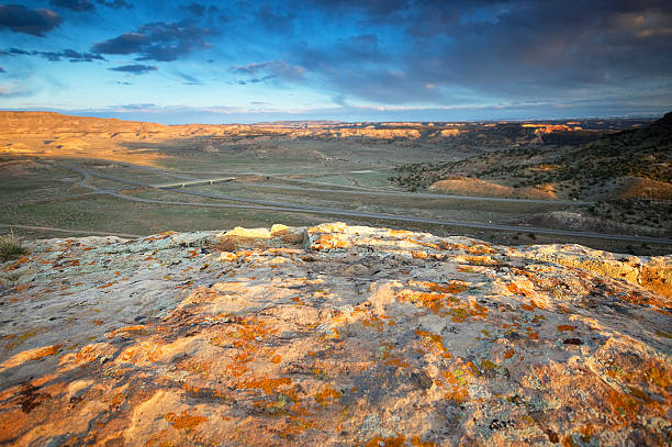 landscape sunset desert "landcape sunset desert with dramatic sky with a shaded interstate highway cutting through the scenery.  taken at rabbit valley, western colorado, usa.  horizontal composition with copy space." sonoran desert desert badlands mesa stock pictures, royalty-free photos & images