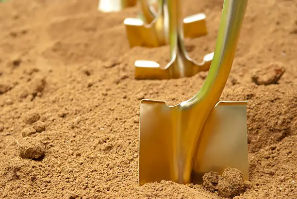 "Gold shovels stuck in the dirt, in preparation of a groundbreaking ceremony"