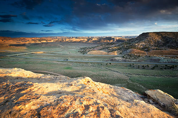 landscape sunset desert "landcape sunset desert with dramatic sky with a shaded interstate highway cutting through the scenery.  taken at rabbit valley, western colorado, usa.  horizontal composition with copy space." sonoran desert desert badlands mesa stock pictures, royalty-free photos & images